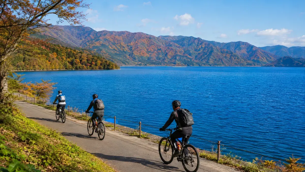 秋の秋田県田沢湖、コバルトブルーの湖面と湖畔をサイクリングする人々の情景