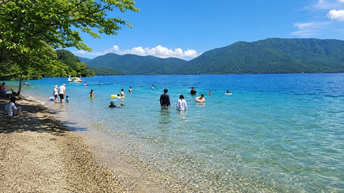 夏の秋田県田沢湖、湖水浴を楽しむ人々で賑わう湖畔の風景