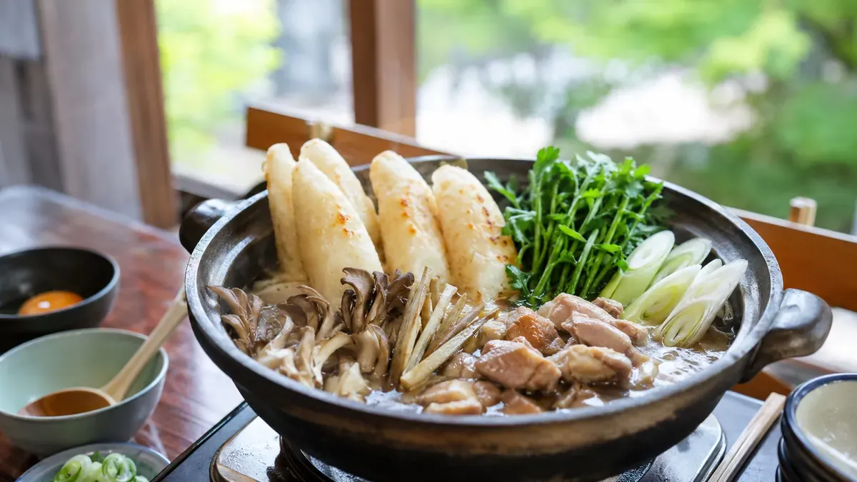 秋田名物きりたんぽ鍋のクローズアップ、比内地鶏の出汁と野菜が煮込まれる様子